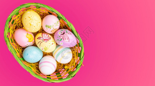 粉色背景柳条篮里装满了复活节鸡蛋背景图片