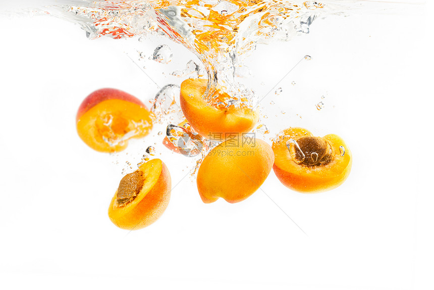 一群杏子掉进水中一半沉入白色背景下有喷水和气泡一群杏子掉进水中一半沉入图片