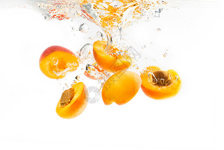 掉进钱袋子一群杏子掉进水中一半沉入白色背景下有喷水和气泡一群杏子掉进水中一半沉入背景