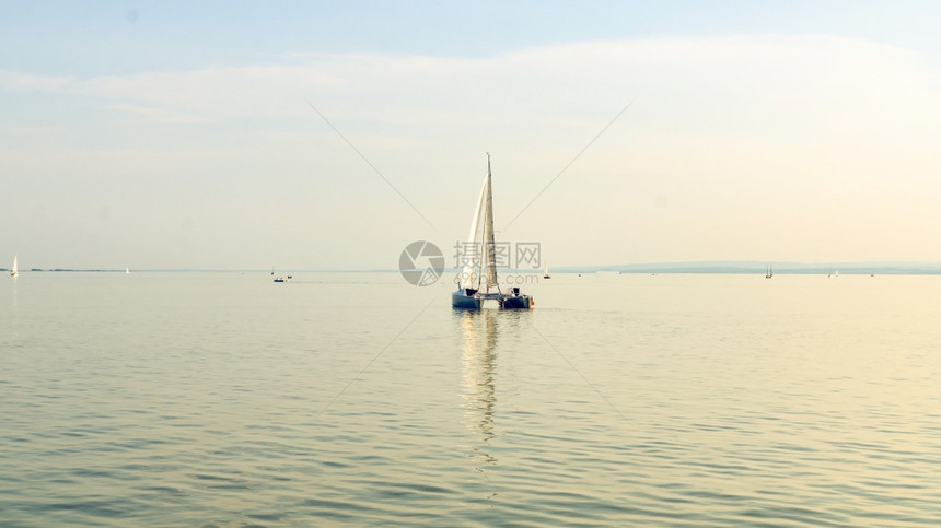 奥地利内西德列尔斯湖上的Catamaran船日落前清空平静的水与日落后空间相仿奥地利内西德列尔斯湖上的Catamaran船图片