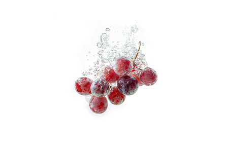 孤立的红葡萄喷洒和沉在水中白色背景空气泡高清图片