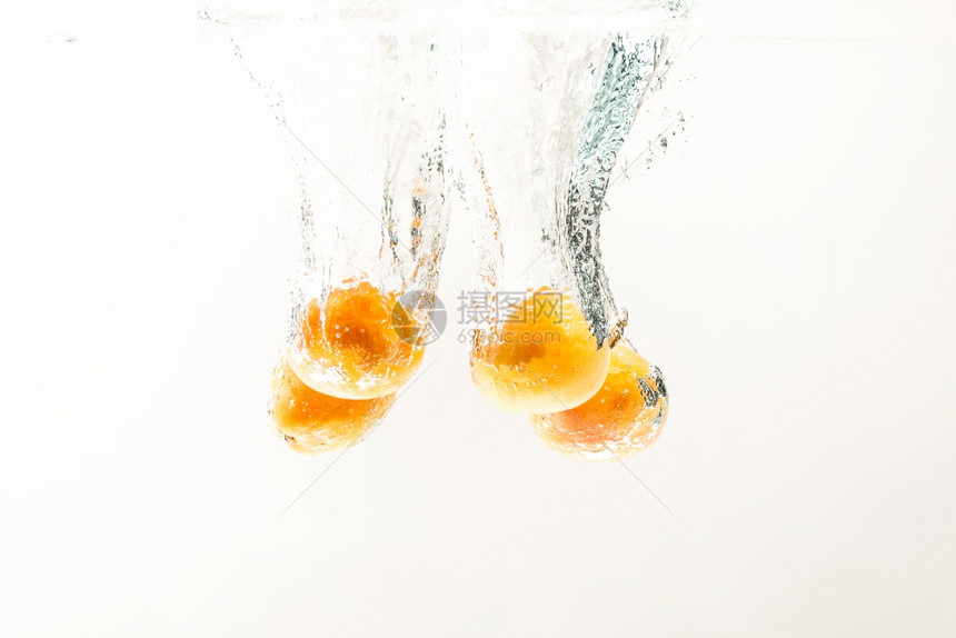 杏子正随着水流而倒在清澈的水中一连串果随着气泡而沉没一连串的果实随着气泡而沉没一连串的杏子随着水流而倒在清澈的水中一连串的果实随图片