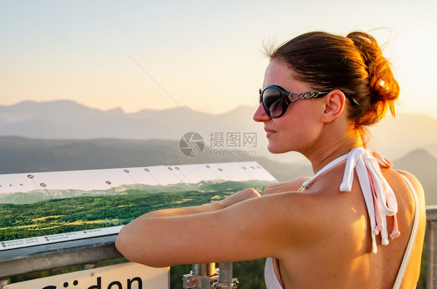 女孩站在卡林西亚的Pyramidenkogel观光塔的甲板上旅游点仰望日落的南阿尔卑斯山女孩站在卡林西亚的Pyramidenko图片