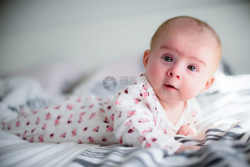 4个月大的女婴躺在床上阳光明媚的卧室看相机图片
