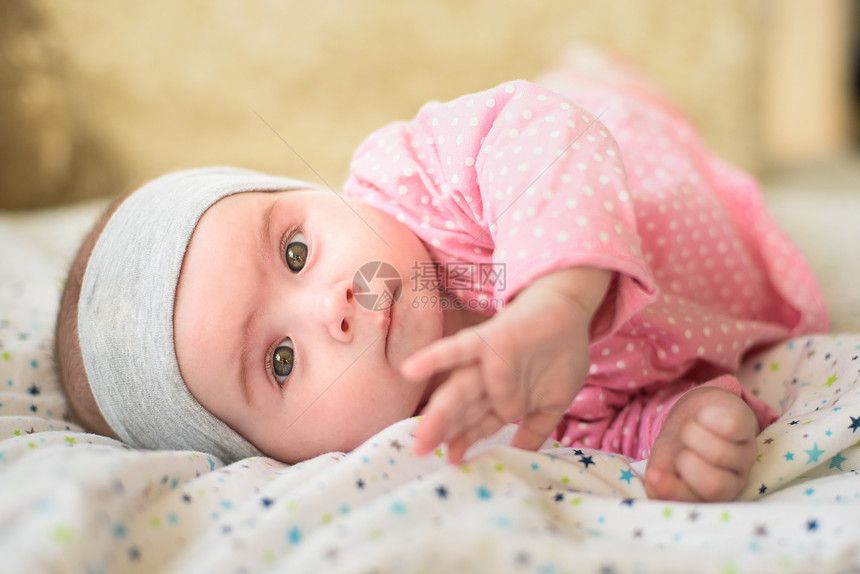 6个月大的女婴在肚子床上被切开6个月大的婴儿头抬起用大眼睛看镜头自然卧室灯光6个月大的女婴在肚子上床被切开6个月大的婴儿用眼睛看图片