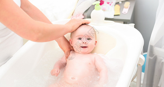 可爱的女婴与母亲一起洗澡仰望大棕色的眼睛和微笑复制空间图片