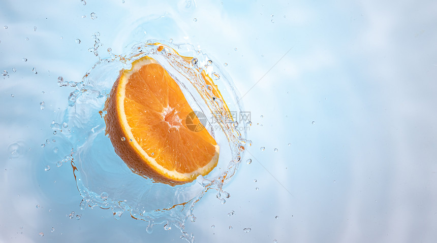 新鲜成熟的半个橙子喷洒到清水中以浅蓝色背景隔绝健康食品概念新鲜成熟的半个橙子水果喷洒到清中图片