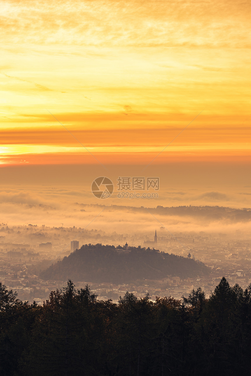 格拉茨市覆盖了秋天清晨日落时雾从周围城市的普劳布茨山上查看格拉茨市覆盖了秋天清晨日落时雾图片