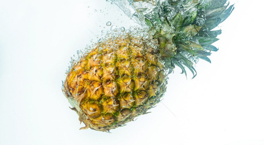 菠萝被丢入白色背景的清水中果喷洒主题图片