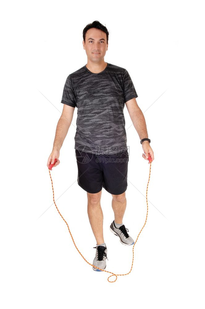 一个站在工作室的年轻人站在工作室里用他的绳子锻炼在一个运动设施里与白种背景隔绝图片