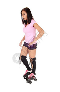 一个穿着短裤的美丽年轻女子站在她的滑溜冰鞋和膝高空孤立的白色背景图片