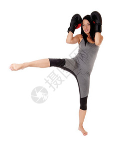 一只瘦的年轻女子穿着礼服带草黑的子踢拳站在一条腿上与白种背景隔绝图片