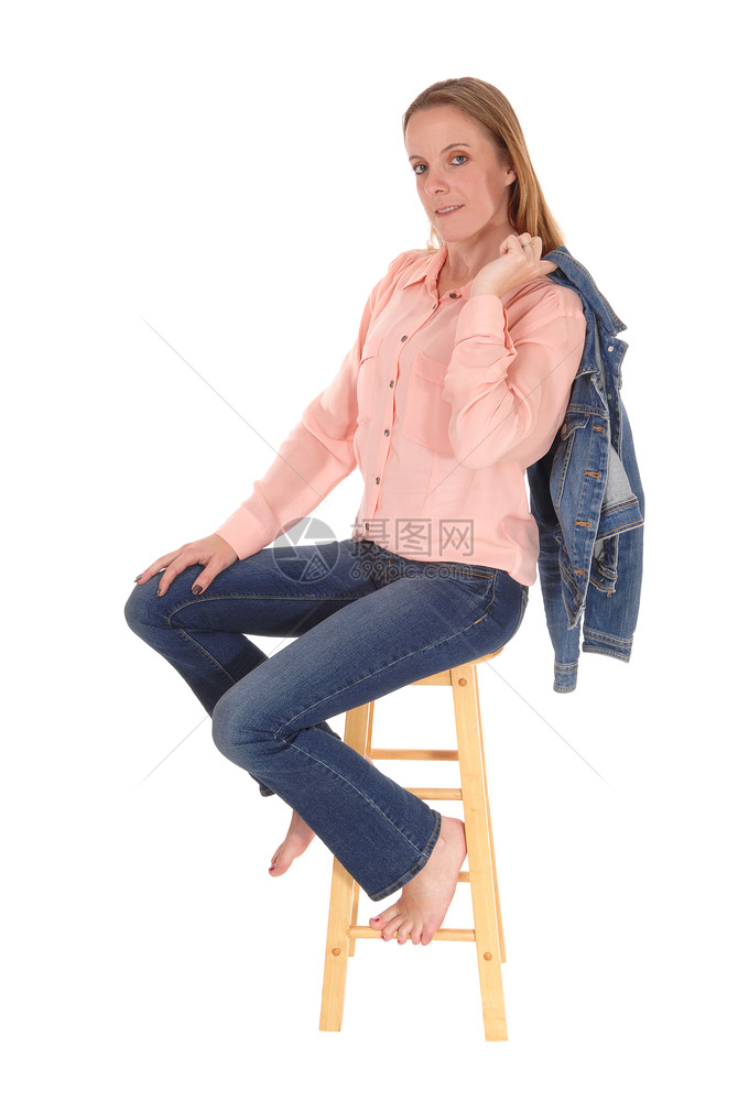 一位瘦的年轻女人赤脚坐在椅子上穿着牛仔裤的椅子上肩穿着牛仔裤外套图片