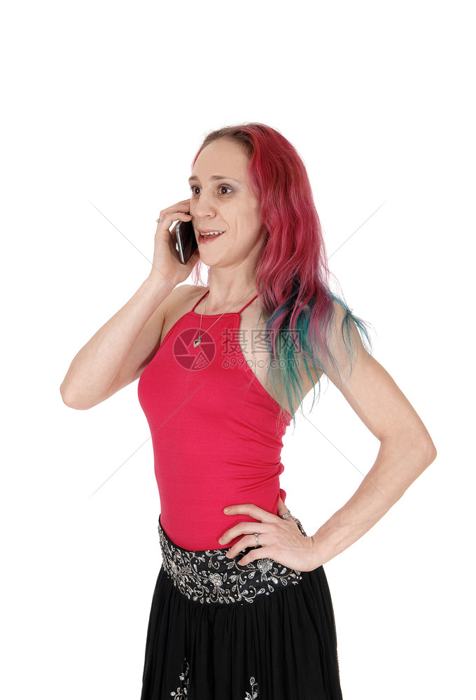 一个穿红色上衣和黑裙子的漂亮年轻美女穿着长的红色头发与白背景隔绝在手机上说话图片