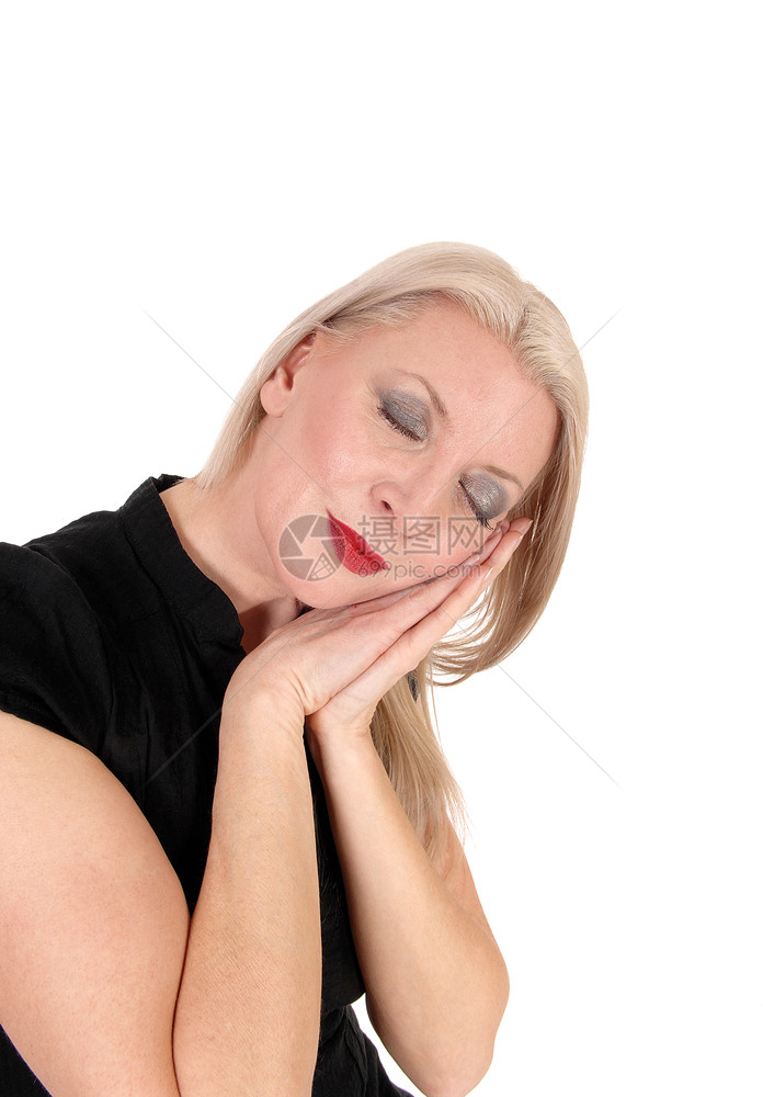 一位美丽的中年妇女坐着头在她的双手上睡着闭眼睛为白种背景而孤立图片