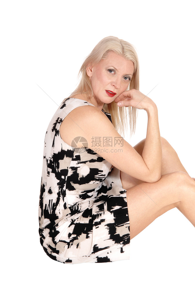一位美丽的中年女子坐在地板上穿着衣服一只手放在她的小鸡上因为白种背景被孤立图片