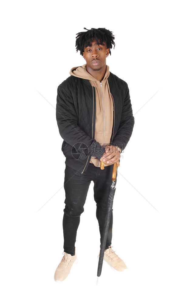 一个穿牛仔裤和夹克的非裔美国人男子站在大学里照顾一个大黑伞图片