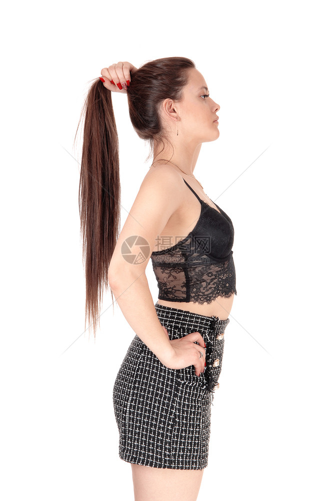 可爱的年轻女子穿着短裤和黑色胸围长的黑发拿着它与白种背景隔绝图片
