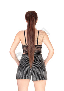 黑短裤年轻的瘦女人穿着短裤和黑胸罩站在后面长着的黑发被白背景隔离背景