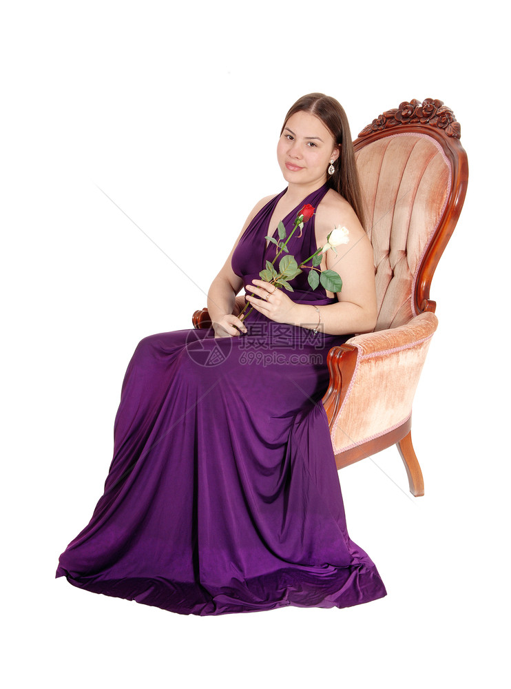 一个漂亮的年轻少女穿着勃根底礼服坐在一把旧扶手椅上拿着两朵玫瑰图片