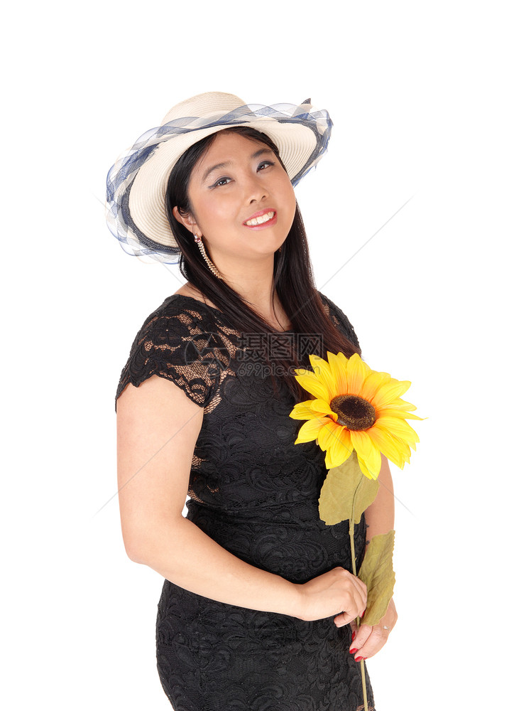 一位美丽的年轻亚洲女穿着黑色裙子和帽手里拿着向日葵微笑与白背景隔绝图片