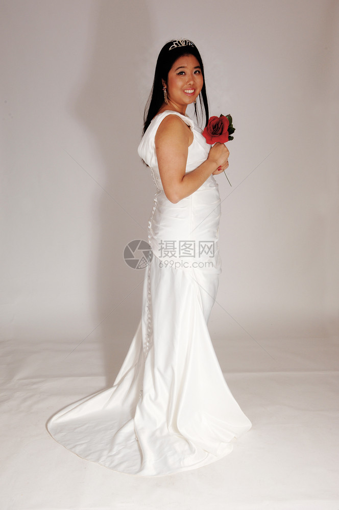 新娘拿着红玫瑰站在白色婚纱上图片