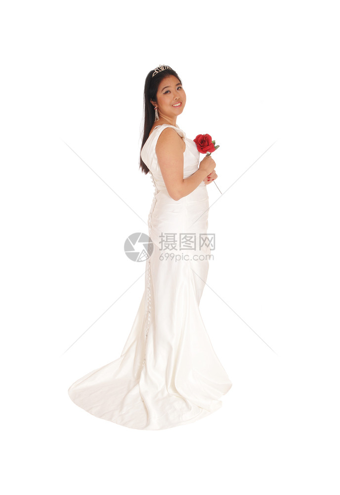 一位美丽的新娘拿着红玫瑰站在白色婚纱上图片