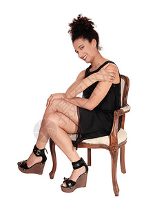 一位美丽的多种族女人穿着黑色短裙坐在一把旧扶椅上笑着带卷发黑图片