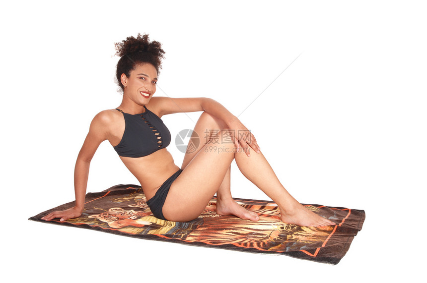 一个瘦的多种族女人坐在工作室的海滩毛巾上穿着黑色比基尼放松着图片