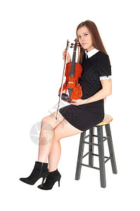 一个穿着黑裙子的漂亮女人拿着她的小提琴看着镜头与白色背景隔绝图片