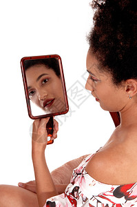 可爱的多种族女人看着自己手握镜子穿夏裙坐图片