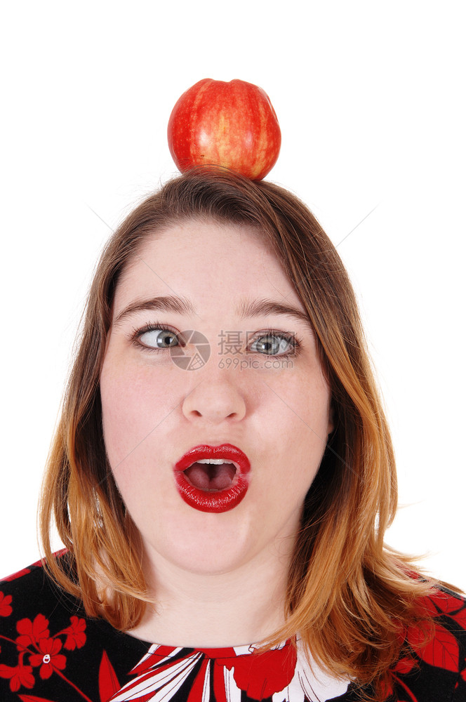 近距离的图像一位年轻女头顶有苹果张开嘴眼睛被白种背景隔绝图片