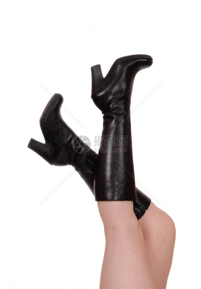 一个女人躺在地板上用长的黑色靴子身体部分抬起双腿在空中举起双腿赤身为白色背景被隔离图片