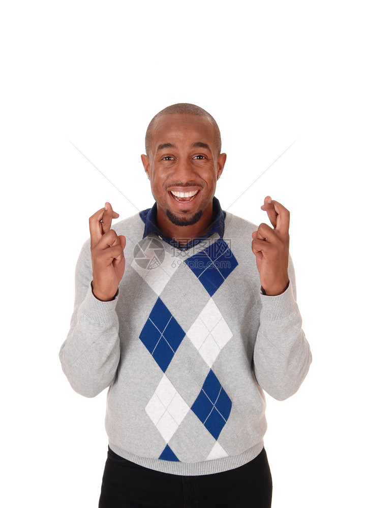 一个笑着的年轻黑人男子站在他的手指交叉希望他有好运孤立的白色背景图片