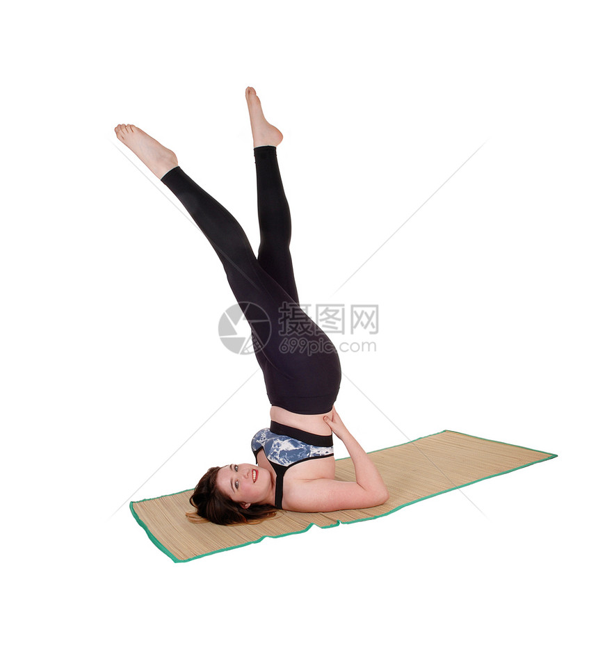 一位美丽的年轻女子在地板上运动她的腿在空中穿着运动服为白种背景被隔离图片