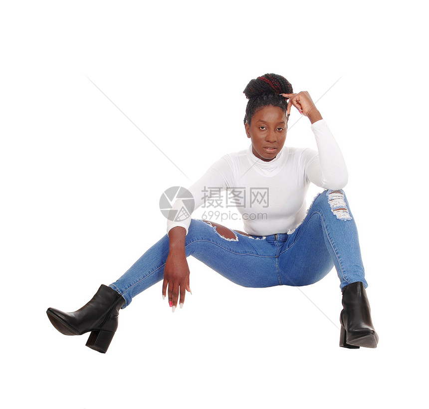 坐在摄影棚地板上穿着牛仔裤白顶着色背景隔离的美丽高非裔美国女人图片