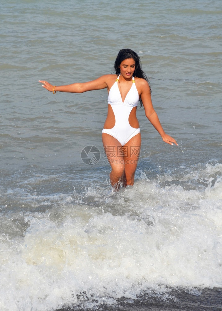 美丽的年轻女子在海洋玩耍穿着白泳衣的海浪玩得开心图片
