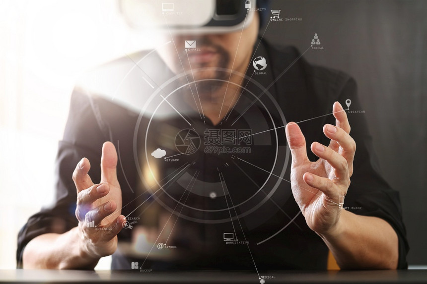 商人在现代办公室佩戴虚拟现实护目镜用手机使VR头戴带屏幕图标的VR头盔图片