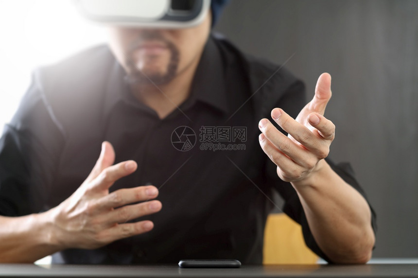 商人在现代办公室佩戴虚拟现实护目镜用手机VR头戴VR盔图片