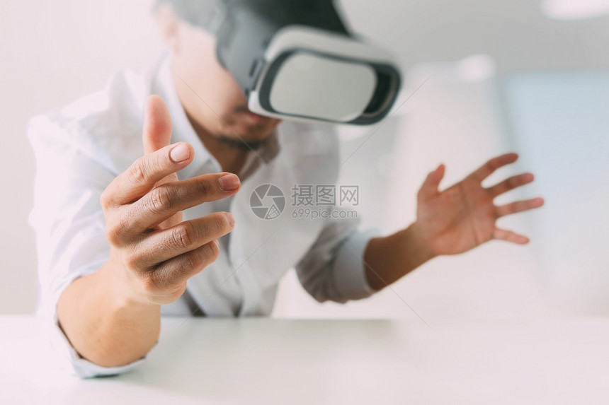 商人在现代办公室佩戴虚拟现实护目镜用手机VR头戴VR盔图片