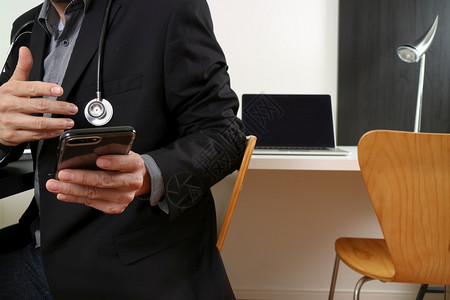 在现代办公室黑暗木制桌使用智能电话和数字平板脑笔记本的智能医生图片