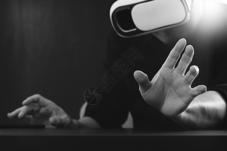 商人在现代办公室戴虚拟现实镜用手机使VR头盔黑白图片