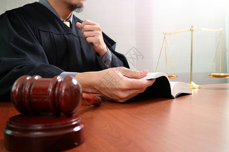 低比例尺法官在庭上使用手镯打开圣书和数字平板电脑在木上使用黄铜比例尺背景