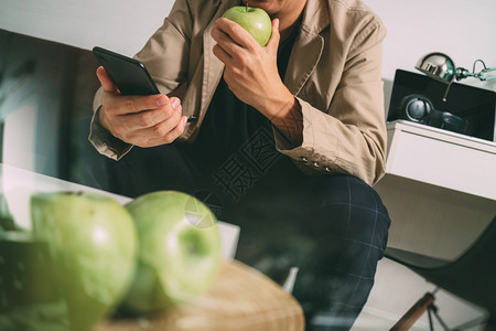 使用智能手机在线支付业务坐在客厅沙发上把绿苹果放在木盘过滤器上图片