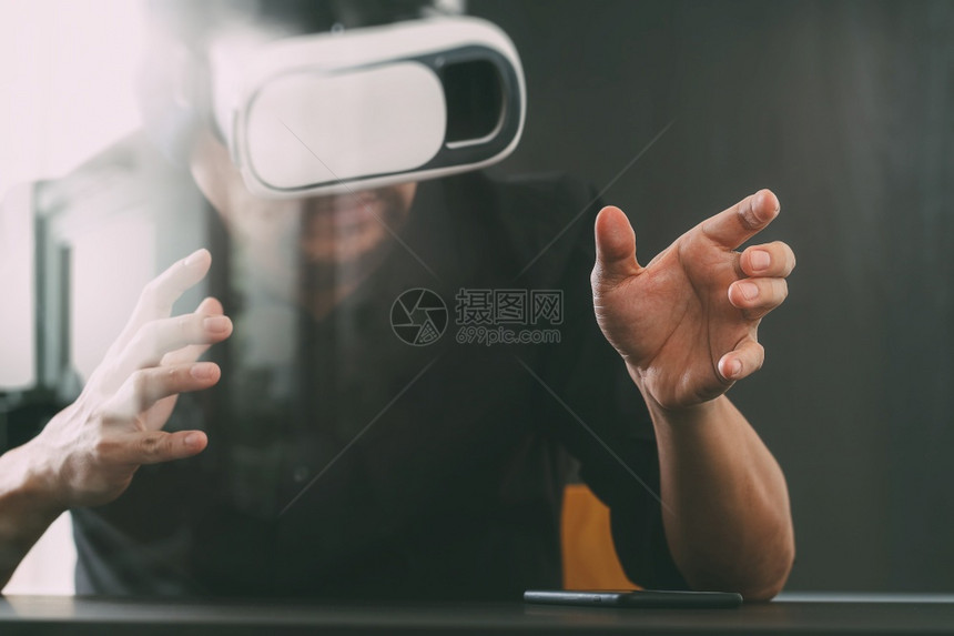 商人在现代办公室佩戴虚拟现实护目镜用手机VR头戴VR盔图片