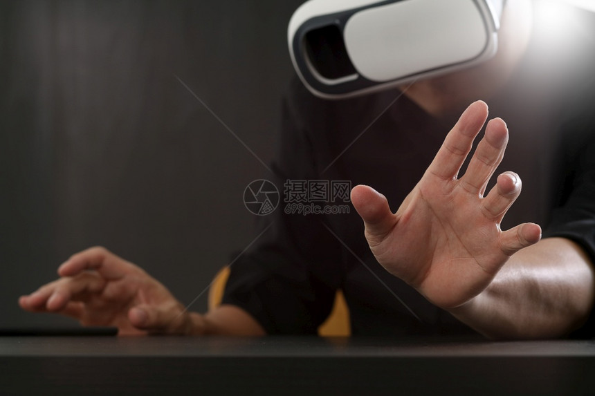 商人在现代办公室佩戴虚拟现实护目镜用手机VR头戴VR盔图片