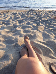 在沙滩上躺着的女性腿部特写图片