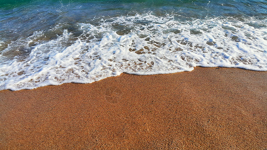 沿海沙砂中含有白泡沫的海水天然封闭背景背景图片