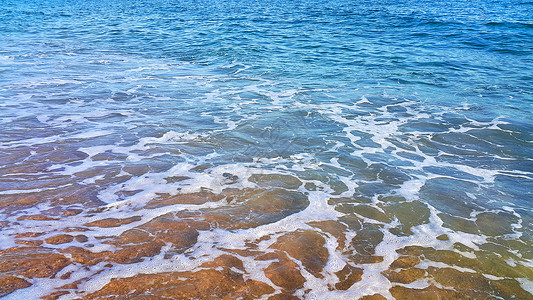 沿海沙滩上含有白泡沫的海水天然封闭背景图片