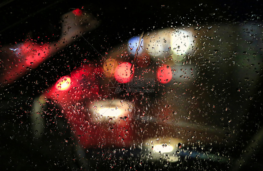 夜晚大城市的灯光穿过车玻璃满是雨滴图片